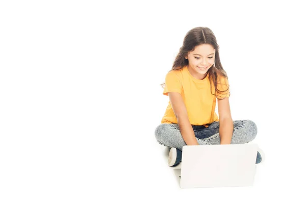 Vista ad alto angolo di bel bambino sorridente seduto e utilizzando computer portatile isolato su bianco — Foto stock