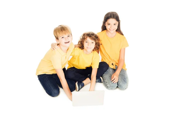 Vista ad alto angolo di adorabili bambini felici utilizzando il computer portatile e sorridendo alla fotocamera isolata sul bianco — Foto stock