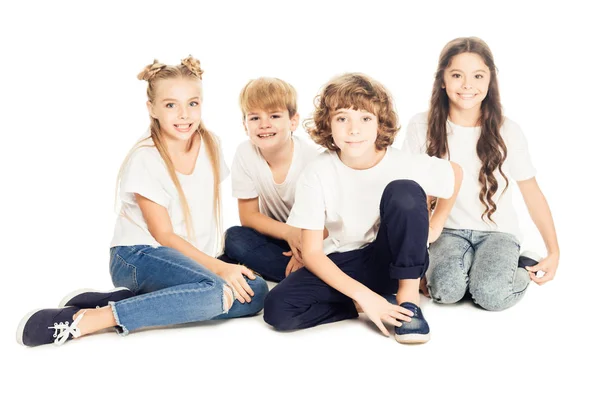 Gruppe schöner, glücklicher Kinder, die zusammen sitzen und isoliert auf Weiß in die Kamera lächeln — Stockfoto