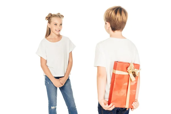 Niño ocultando caja de regalo detrás de nuevo para presentar a un amigo aislado en blanco - foto de stock