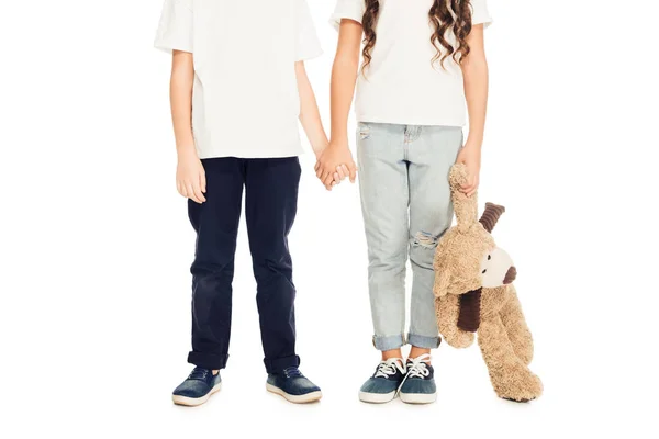 Imagem cortada de crianças de mãos dadas e ursinho isolado no branco — Fotografia de Stock