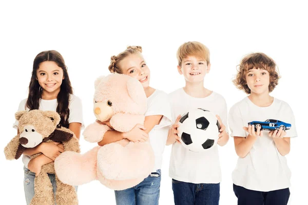 Niños sonrientes sosteniendo juguetes y mirando a la cámara aislada en blanco - foto de stock