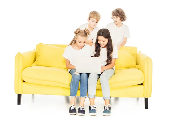 Smiling friends using laptop on yellow sofa isolated on white — Stock Photo