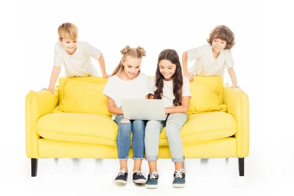 Niños usando portátil en sofá amarillo aislado en blanco - foto de stock