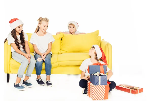 Lächelnde Kinder in Weihnachtsmützen mit Geschenken auf weißem Grund — Stockfoto