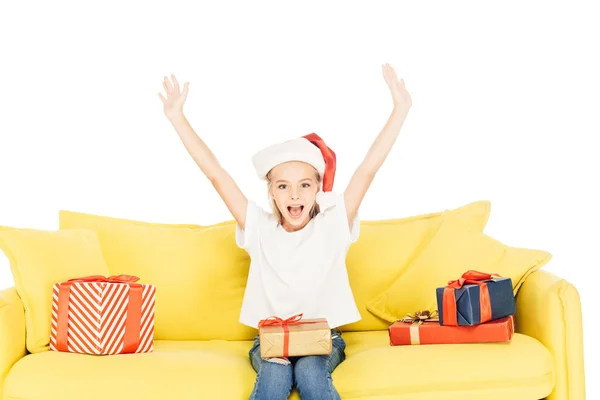 Glücklich liebenswertes Kind mit Weihnachtsmannmütze schreit mit erhobenen Händen isoliert auf weiß, Blick in die Kamera — Stockfoto