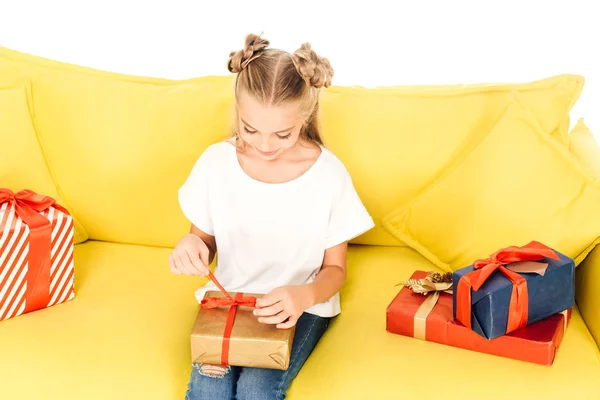 High angle view of adorable child opening present on yellow sofa isolated on white — Stock Photo