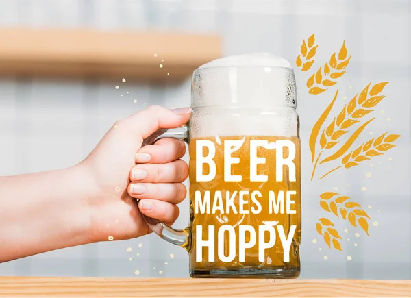 Partial view of female bartender putting mug of light beer with foam on bar counter  with 