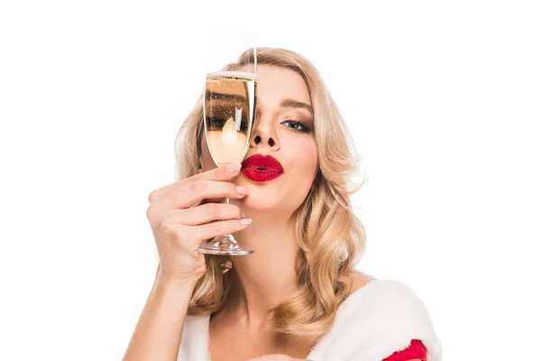 Portrait of young woman in christmas dress covering face by champagne glass isolated on white — Stock Photo