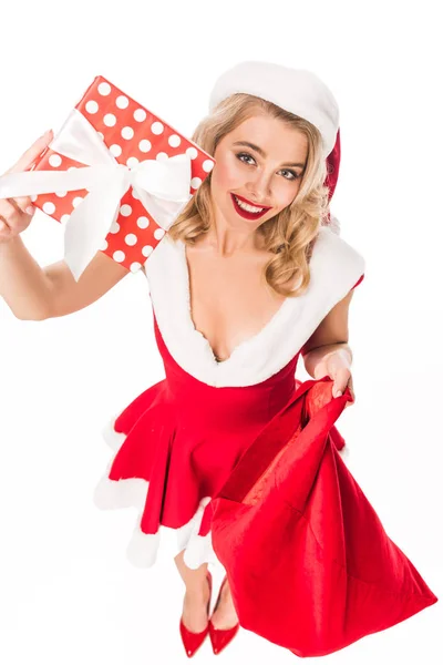 Vista de ángulo alto de la chica sexy de santa en el sombrero de Navidad que muestra la caja de regalo y la bolsa de sujeción aislada en blanco - foto de stock