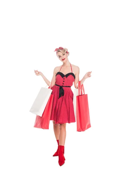 Mujer joven en ropa retro pin up con bolsas de compras aisladas en blanco - foto de stock
