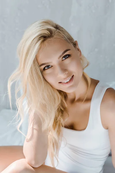 Портрет красивої молодої блондинки в нижній білизні, посміхаючись на камеру в спальні — стокове фото
