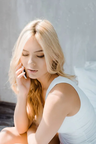 Attractive blonde girl in underwear talking by smartphone in bedroom — Stock Photo