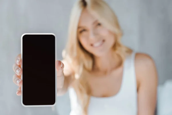 Vue rapprochée de la jeune femme montrant un smartphone avec écran blanc — Photo de stock