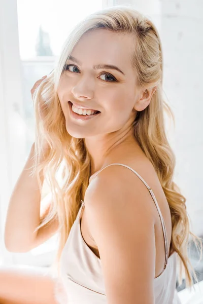 Portrait de belle jeune femme blonde souriant à la caméra dans la chambre — Photo de stock