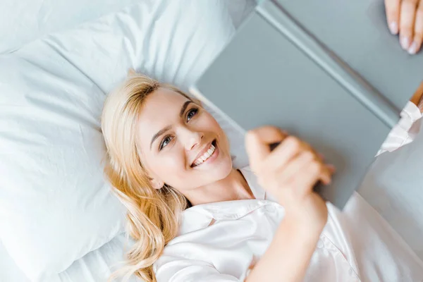 Vista superior da jovem mulher feliz deitada na cama e livro de leitura — Fotografia de Stock