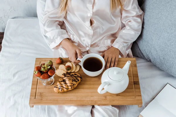 Abgeschnittenes Bild einer Frau im Pyjama beim Frühstück im Bett — Stockfoto