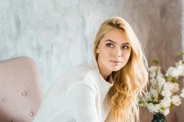 Porträt einer schönen Frau im Pullover, die auf einem Sessel im Schlafzimmer sitzt und wegschaut — Stockfoto