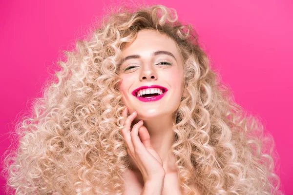 Atractiva chica desnuda con el pelo largo rizado sonriendo a la cámara aislada en rosa - foto de stock
