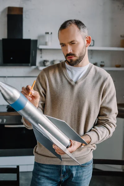 Красивий інженер дивиться на нову ракетну модель вдома — стокове фото