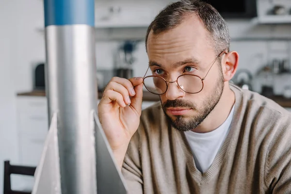 Porträt eines gut aussehenden Ingenieurs, der zu Hause über eine Brille auf ein Raketenmodell blickt — Stockfoto