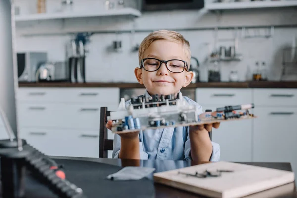 Adorable boy holding motherboard at table at home — Stock Photo