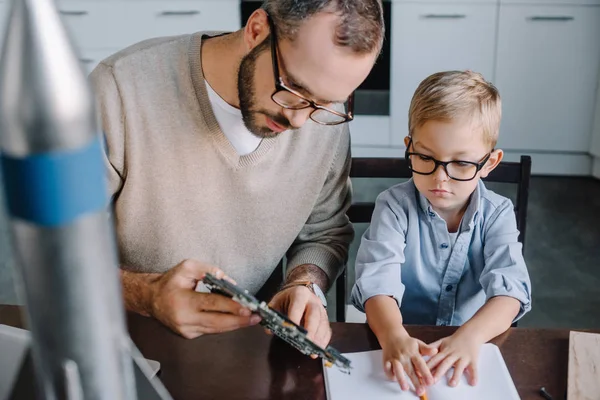 Pai e filho reparando microcircuito juntos em casa — Fotografia de Stock