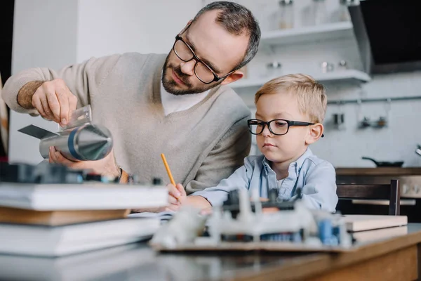 Padre e figlio in occhiali modellazione razzo a casa — Foto stock