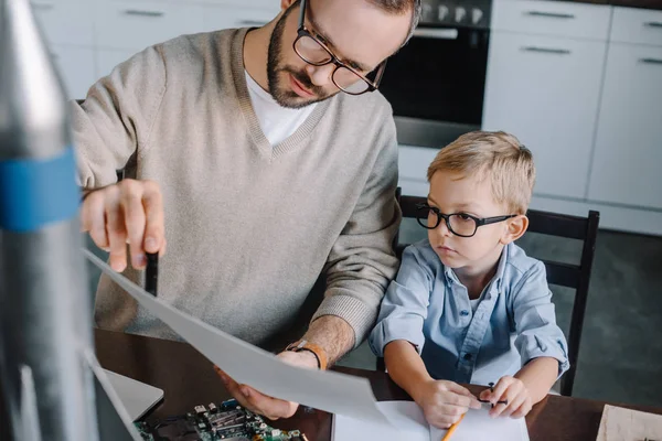 Padre e figlio modellazione razzo e guardando cianografia a casa — Foto stock