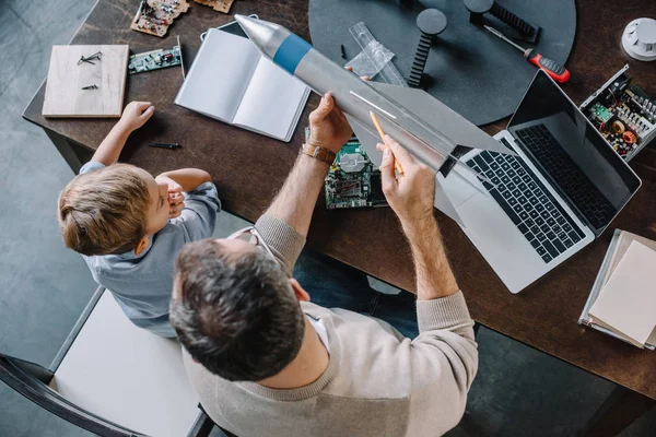 Overhead view of father and son modeling rocket at home — Stock Photo