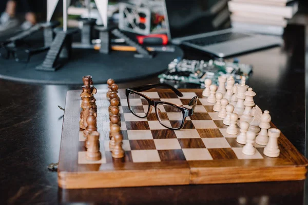 Wooden chess board with glasses on table in living room — Stock Photo