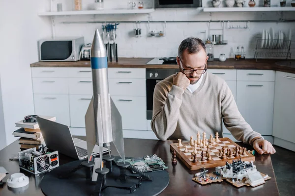 Pensive handsome man looking at chess board at home — Stock Photo