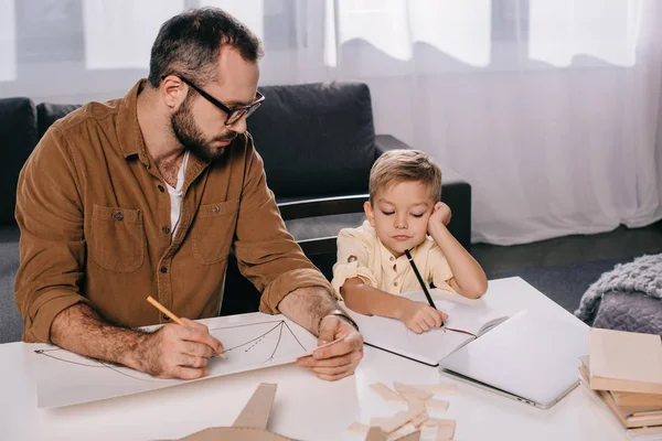 Padre e piccolo figlio disegno mentre modellare insieme a casa — Foto stock