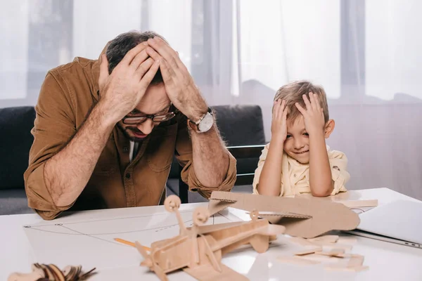 Agotado padre e hijo modelando juntos en casa - foto de stock