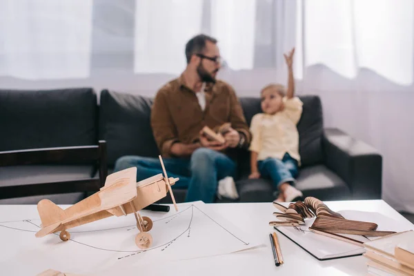 Nahaufnahme eines hölzernen Flugzeugmodells und glücklicher Vater mit Sohn dahinter — Stockfoto