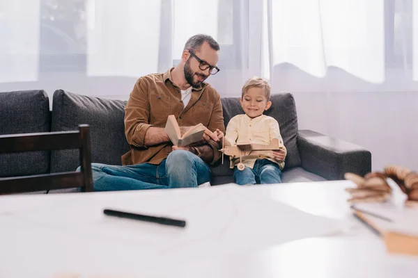 Pai feliz e filho brincando com modelo de avião de madeira em casa — Fotografia de Stock