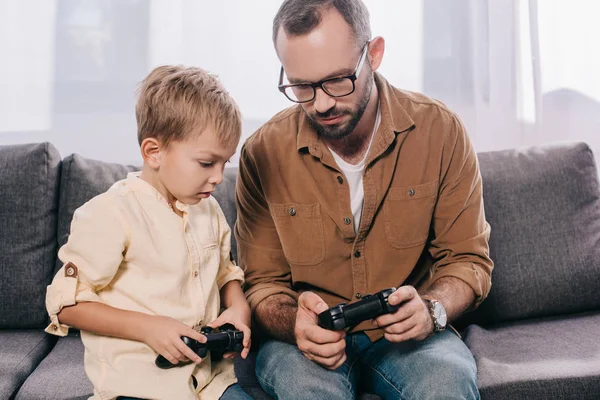 Vater und süßer kleiner Sohn spielen zu Hause mit Steuerknüppeln — Stockfoto