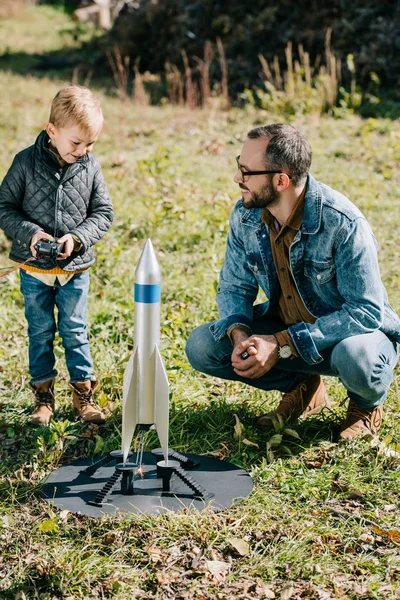 Щасливий батько і маленький син запускає модель ракети на відкритому повітрі — стокове фото