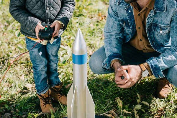 Обрезанный снимок отца и маленького сына, запускающих модель ракеты на открытом воздухе — стоковое фото