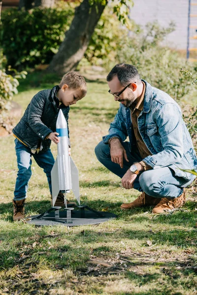 Щасливий батько і син грають разом з моделлю ракети в сонячний день — стокове фото
