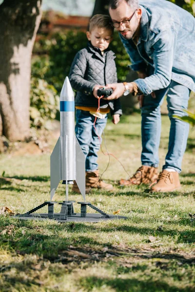 Батько і син запускають модель ракети в сонячний день — стокове фото