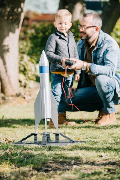 Крупным планом модель ракеты и отец с сыном, играющие сзади — стоковое фото