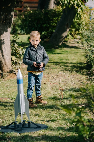 Милий маленький хлопчик запускає модель ракети на відкритому повітрі — стокове фото