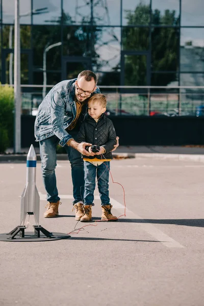 Happy father and son launching model rocket outdoor — Stock Photo