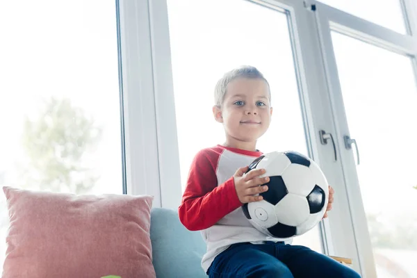 Portrait of cute kid with soccer ball in hands at home — Stock Photo