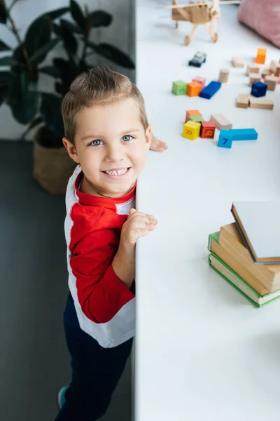 Vista ad alto angolo del bambino in piedi in superficie con libri e blocchi colorati a casa — Foto stock