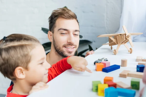 Side view of father and cute little son playing with wooden blocks together at home — Stock Photo