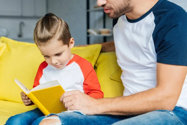 Visão parcial do pai livro de leitura para o pequeno filho em casa — Fotografia de Stock