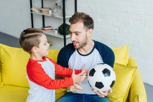 Портрет отца и сына с футбольным мячом дома — стоковое фото