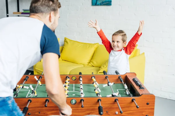 Glücklicher kleiner Junge spielt zu Hause mit Vater Tischkicker — Stockfoto